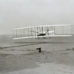 Wright Brothers old plane on sand with person