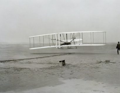 Wright Brothers old plane on sand with person
